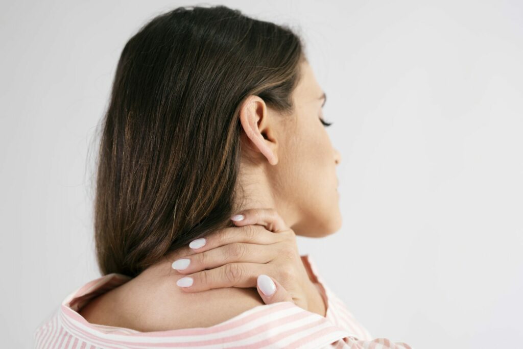 Rear view of young woman suffering from neck pain